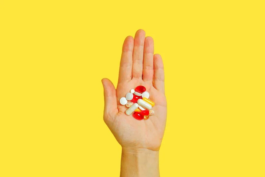 A hand holding assorted supplement pills